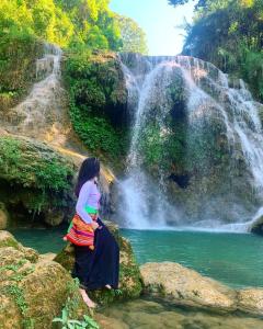 Una ragazza in piedi davanti a una cascata di LePont Mu Waterfall Bungalow a Hòa Bình
