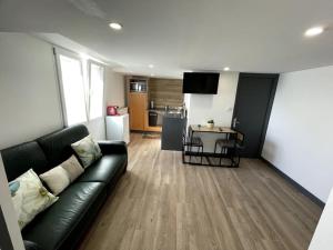 salon z czarną skórzaną kanapą i kuchnią w obiekcie Douceur Drômoise appartement avec une chambre w mieście Montélimar
