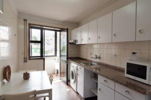 - une cuisine avec des placards blancs, un évier et une table dans l'établissement Quarto privativo perto Centro Porto, à Porto
