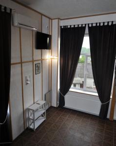 Habitación con ventana grande y TV. en Дворівневі Апартаменти-Лофт у Старому місті, en Kamianets-Podilskyi