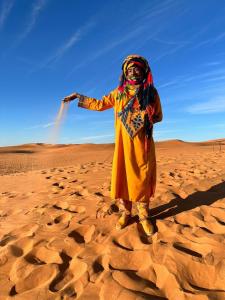 a woman standing in the sand in the desert at Sahara Ousis Camp in Merzouga