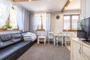 a living room with a black leather couch and a table at Apartament u Majerczyka in Zakopane