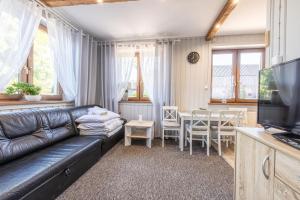 a living room with a black leather couch and a table at Apartament u Majerczyka in Zakopane