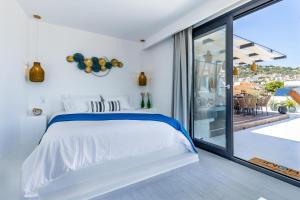 a white bedroom with a bed and a large window at To Nissi in Skopelos Town