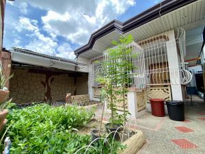 Teo’s Spacious and Affordable Home in Cabanatuan في كاباناتوان: حديقة فيها قفص طيور وبعض النباتات