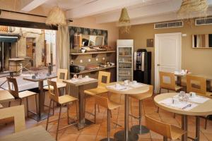 un ristorante con tavoli e sedie in una stanza di The Originals Boutique, Hôtel Cassitel, Cassis a Cassis