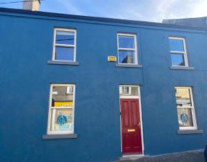 un edificio azul con una puerta roja y ventanas en Church View House, en Kells