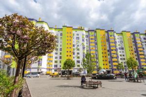 un grand bâtiment jaune et blanc avec bancs et arbres dans l'établissement 093 ЖК Щасливий нові апартаменти біля Кільцевоі, à Kiev