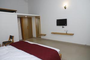 GarudeshwarにあるSomnath innのベッドルーム1室(ベッド1台、壁掛けテレビ付)