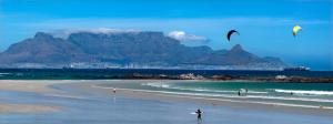 Cape Town的住宿－Ocean Vibes，站在海滩上,飞风筝的人