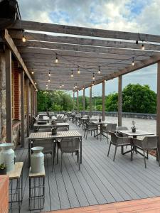 una terraza de madera con mesas, sillas y luces en Hotel Pernigele, en Jelgavkrasti