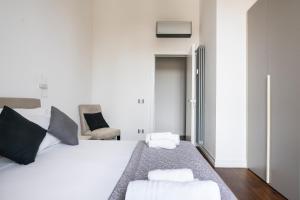 a white bedroom with a bed and a chair at San Marco Black Appartamento Luxury con Terrazzo e Parcheggio su richiesta in Florence