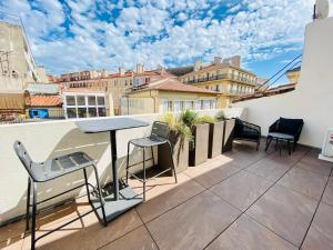 een patio met een tafel en stoelen op een balkon bij LES TOITS DU VIEUX-PORT in Marseille