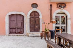 twee deuren van een roze gebouw met banken en tafels bij Il Dolce Rifugio. Piazza principale di Leonessa in Leonessa