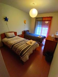 a bedroom with two beds and a table and a window at CASA DIAS in Vila do Bispo
