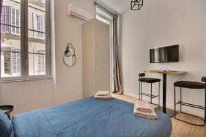 um pequeno quarto com uma cama azul e uma mesa em LES TOITS DU VIEUX-PORT em Marselha