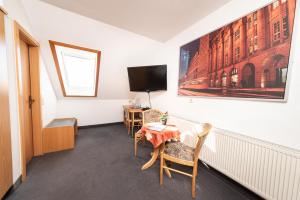 a room with a table and chairs and a tv at Pension am Sandberg in Leipzig