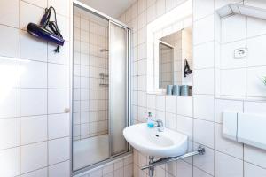 y baño blanco con lavabo y ducha. en Pension am Sandberg, en Leipzig