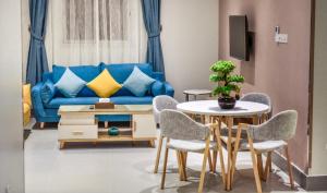 Amar suites في الرياض: غرفة معيشة مع أريكة زرقاء وطاولة وكراسي