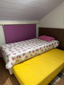 um pequeno quarto com uma cama e um colchão amarelo em MARA Maranduba! Apê c/ Piscina. em Ubatuba