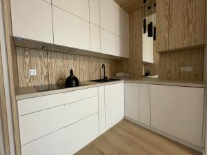 a white kitchen with white cabinets and wooden walls at Apartament Pirat in Ostróda