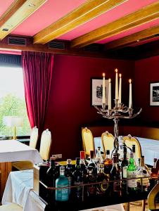 ein Esszimmer mit einem Tisch mit Flaschen und Kerzen in der Unterkunft Landhotel Bellevue in Wolfshausen