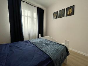 ein Schlafzimmer mit einem blauen Bett und einem Fenster in der Unterkunft Apartament Pirat in Ostróda
