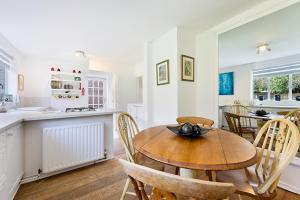 Pass the Keys Hidden Cottage in Esher, West End في إيشر: مطبخ مع طاولة وكراسي خشبية في مطبخ