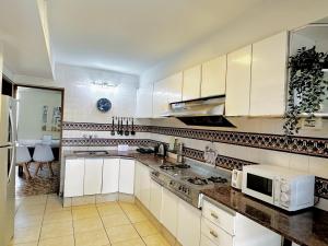 cocina con armarios blancos, fregadero y microondas en Casa en la mejor ubicación! en Mendoza