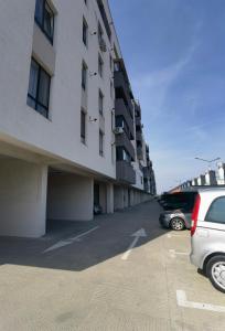un parking avec des voitures garées à côté d'un bâtiment dans l'établissement Atractiv Apartaments, à Chiajna
