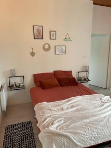 1 dormitorio con 1 cama con sábanas rojas y cuadros en la pared en Le loft, en Bouillargues