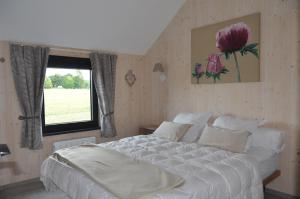 Un dormitorio con una gran cama blanca y una ventana en La clef des bois, en Paliseul