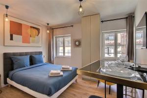 een slaapkamer met een bed, een bureau en ramen bij LES TOITS DU VIEUX-PORT in Marseille