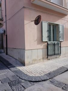 a pink building with a window and a shutter at Casa del papà in Noto