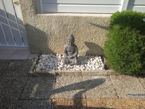 a statue sitting on rocks in front of a house at Zenatitude in Marseillan