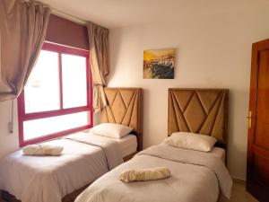 two beds in a room with a window at Amazing Appartement au centre ville en face HILTON & Gare Train de TGV de TANGER in Tangier