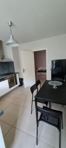 uma cozinha com uma mesa preta e cadeiras num quarto em Appartement Meylan em Meylan