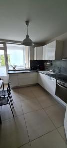 a kitchen with white cabinets and a large window at Appartement Meylan in Meylan