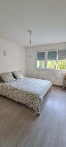 um quarto branco com uma cama e 2 janelas em Appartement Meylan em Meylan