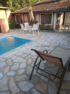 a patio with a chair and a swimming pool at Casa com Piscina a 100 m. de Camburizinho in Camburi