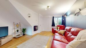 uma sala de estar com um sofá vermelho e uma televisão em Duxford Deluxe 