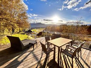 a wooden deck with a table and chairs and the sun at Haus an der Drau nahe Velden / App. DRAU byTILLY in Velden am Wörthersee