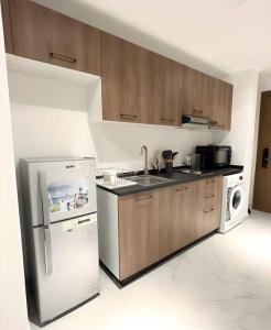 a kitchen with wooden cabinets and a white refrigerator at Classy Studio in Masdar City in Al Qurayyah