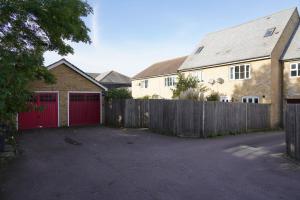 una casa con puertas de garaje rojas y una valla en Duxford Deluxe 
