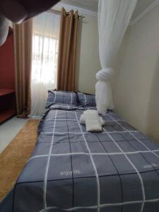 a bedroom with a bed with blue sheets and a window at consortium apartments in Bungoma