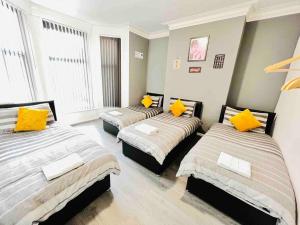 - 3 lits dans une chambre avec des oreillers jaunes dans l'établissement NEW Spacious 8 Bedroom House Perfect For Groups, Hen, Stag, Football & More!, à Liverpool