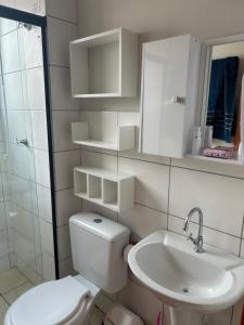 a white bathroom with a toilet and a sink at Apartamento ACOMODA 5 PESSOAS próximo ao Uberlândia Shopping in Uberlândia