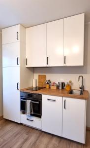 a kitchen with white cabinets and a black oven at Entire Apartment + 2 Rooms + Self Check-in in Tallinn