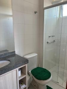 baño con ducha y aseo con alfombra verde en Apartamento central aconchegante.Sinta-se em casa!, en Guarapuava