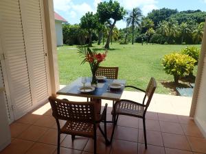 a table and chairs on a patio with a view of a yard at Pierre & Vacances Antigua 03 in Sainte-Luce